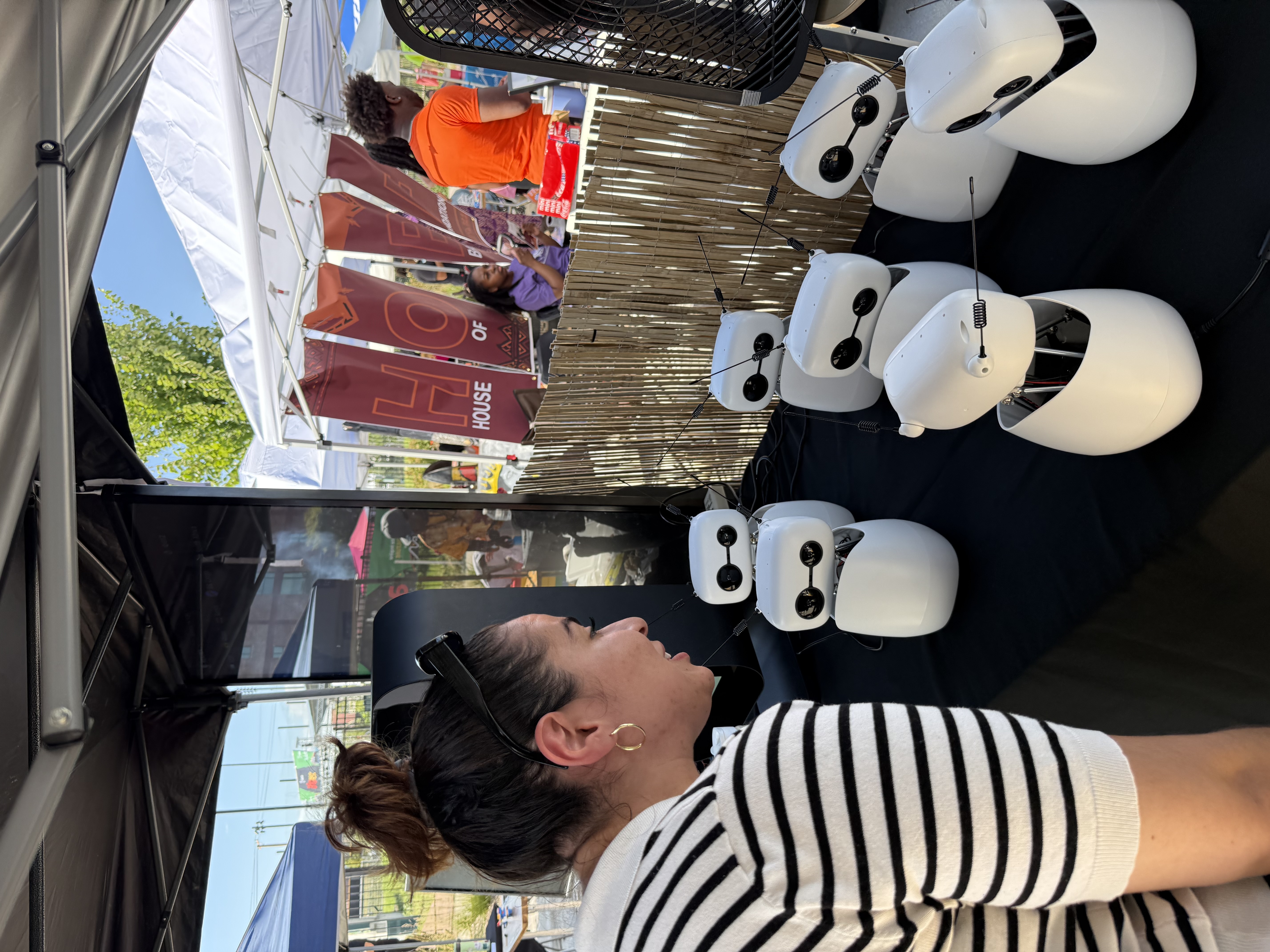 A visitor leans to the units' eye level. The tent directly behind the table belongs to the House of Bah Foundation, one of the festival's hosts.