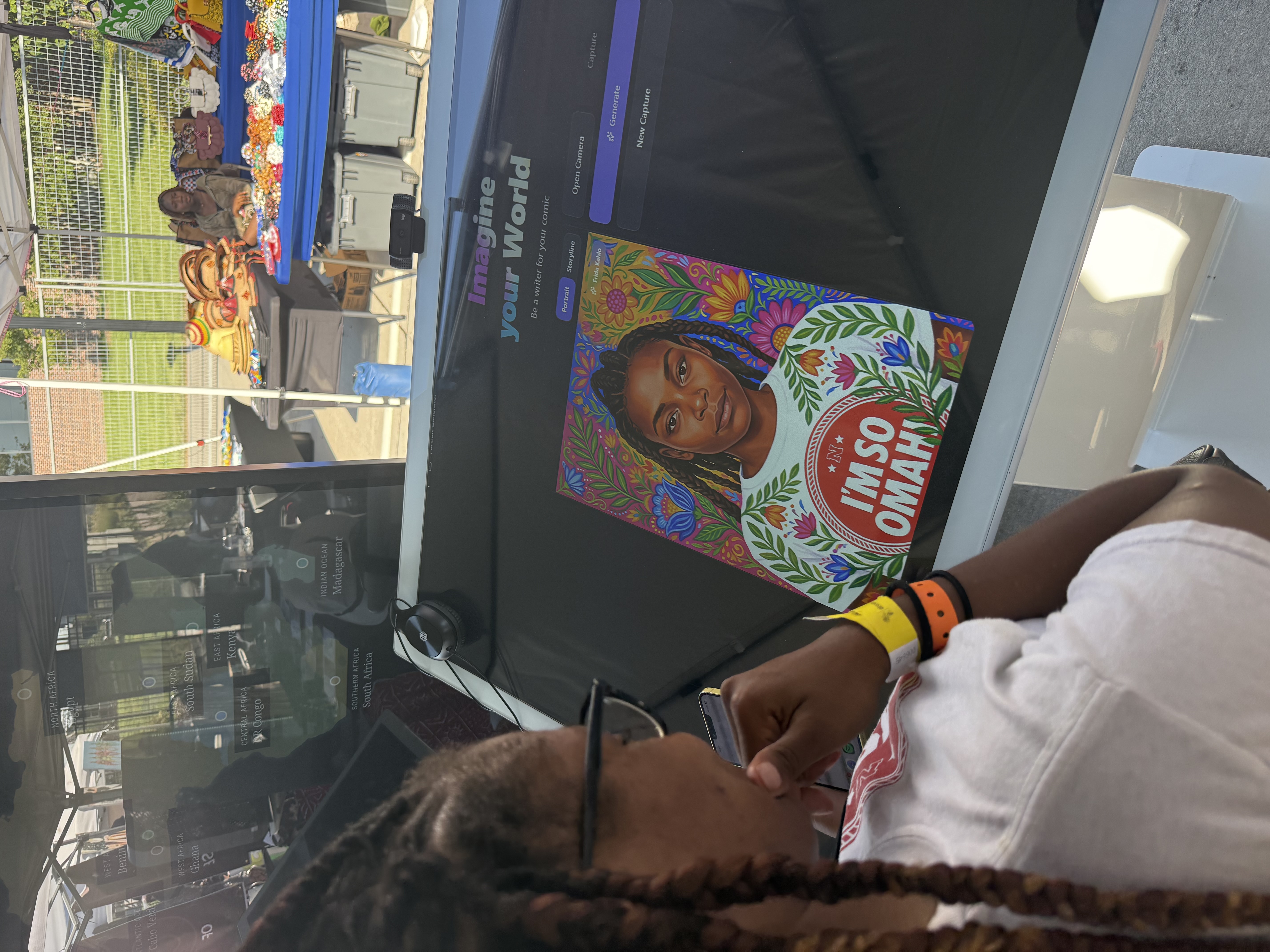 An attendee reviews a stylized portrait on the Artist's Lens touchscreen, one of two outputs the kiosk produced from a live photo taken at the table.